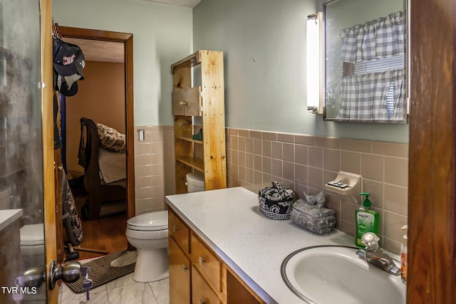full bath featuring toilet, wainscoting, tile walls, and vanity
