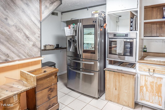 kitchen featuring light tile patterned floors, visible vents, appliances with stainless steel finishes, and a textured ceiling