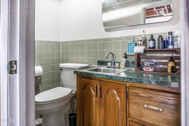 half bathroom featuring toilet, wainscoting, tile walls, and vanity