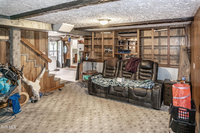 sitting room featuring stairs, beamed ceiling, carpet flooring, and wooden walls
