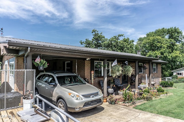 view of front of house featuring metal roof, a carport, brick siding, and a front lawn