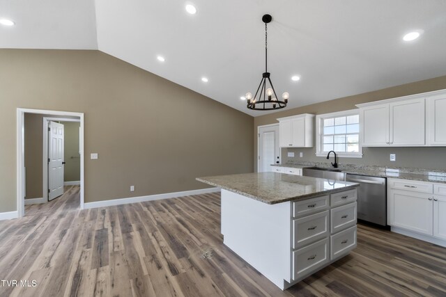 kitchen featuring a center island, lofted ceiling, stainless steel dishwasher, white cabinetry, and a sink