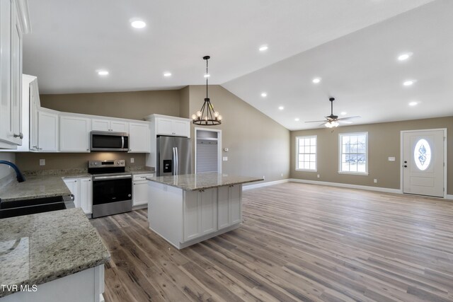 kitchen featuring white cabinets, appliances with stainless steel finishes, a center island, light wood-type flooring, and a sink