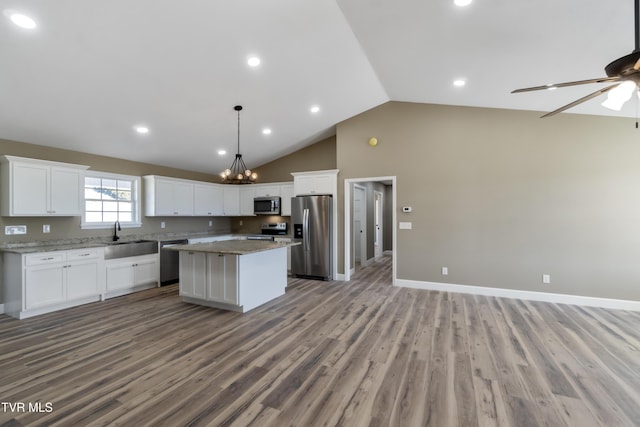 kitchen featuring a sink, white cabinets, open floor plan, appliances with stainless steel finishes, and a center island