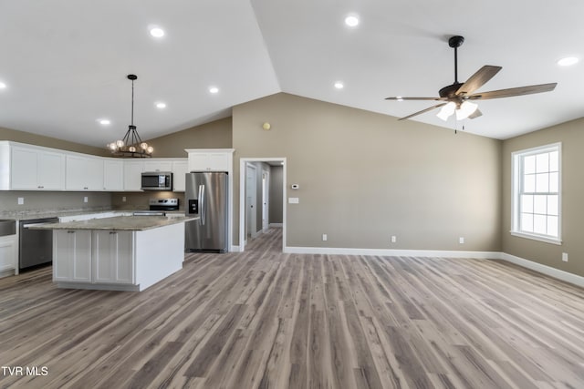 kitchen featuring open floor plan, stainless steel appliances, a kitchen island, and white cabinetry