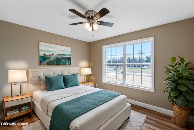 bedroom with ceiling fan, baseboards, and wood finished floors