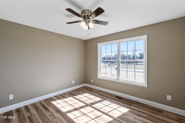 spare room with ceiling fan, wood finished floors, visible vents, and baseboards