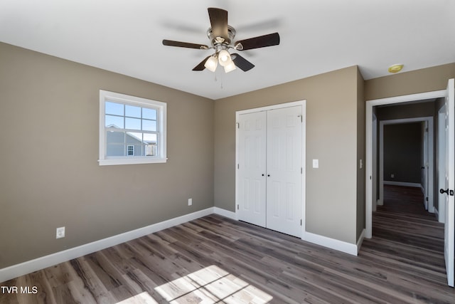 unfurnished bedroom featuring a closet, wood finished floors, a ceiling fan, and baseboards