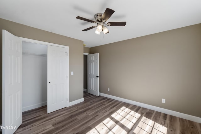 unfurnished bedroom with ceiling fan, a closet, wood finished floors, and baseboards