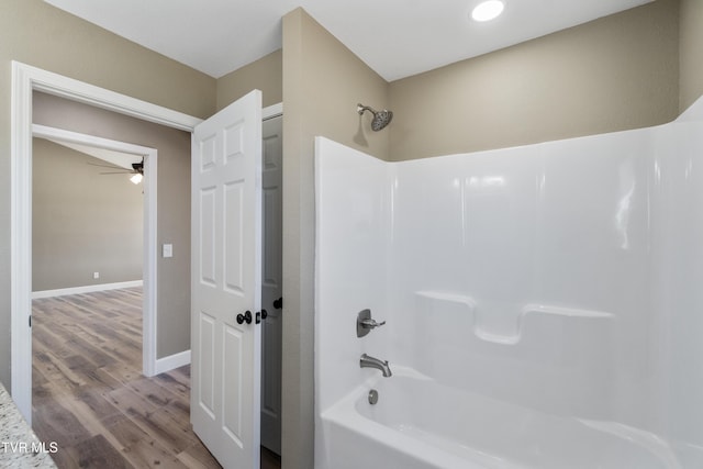 full bathroom featuring shower / washtub combination, wood finished floors, a ceiling fan, and baseboards