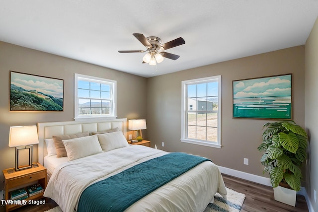 bedroom featuring a ceiling fan, multiple windows, baseboards, and wood finished floors