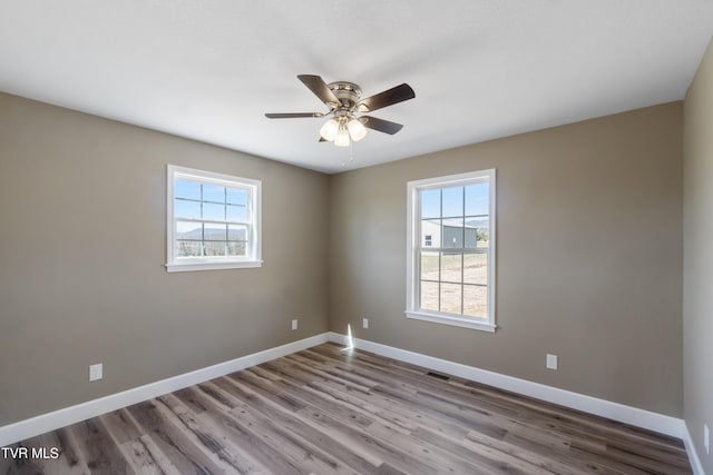 spare room with a ceiling fan, baseboards, and wood finished floors