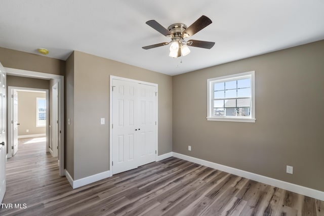 unfurnished bedroom with a closet, multiple windows, and baseboards