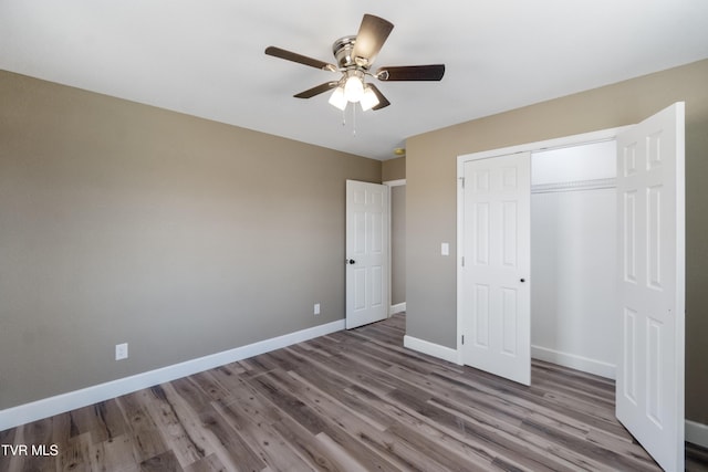 unfurnished bedroom with ceiling fan, a closet, wood finished floors, and baseboards