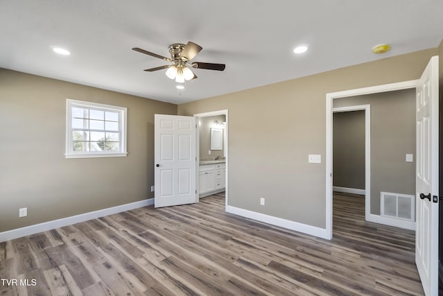 unfurnished bedroom featuring baseboards, connected bathroom, visible vents, and wood finished floors