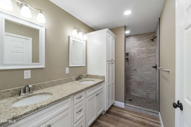 full bath with a tile shower, a sink, and wood finished floors