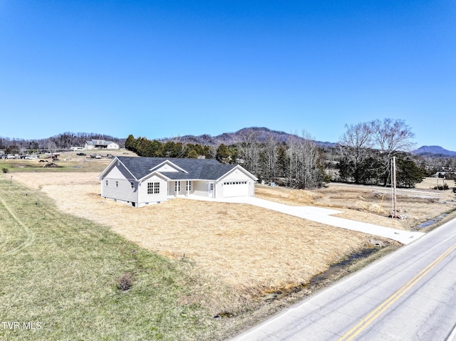 view of front facade with a garage, a mountain view, concrete driveway, and a front yard