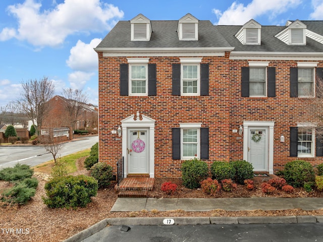 view of front of house featuring a shingled roof and brick siding