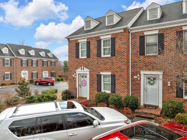 view of front of house featuring brick siding and a shingled roof