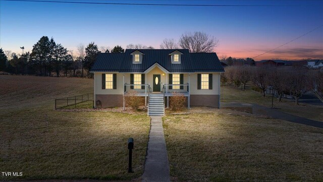 view of front of property featuring metal roof, covered porch, stairs, fence, and a front lawn