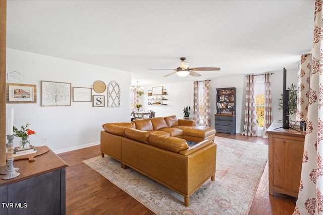 living area with a textured ceiling, ceiling fan, wood finished floors, and baseboards