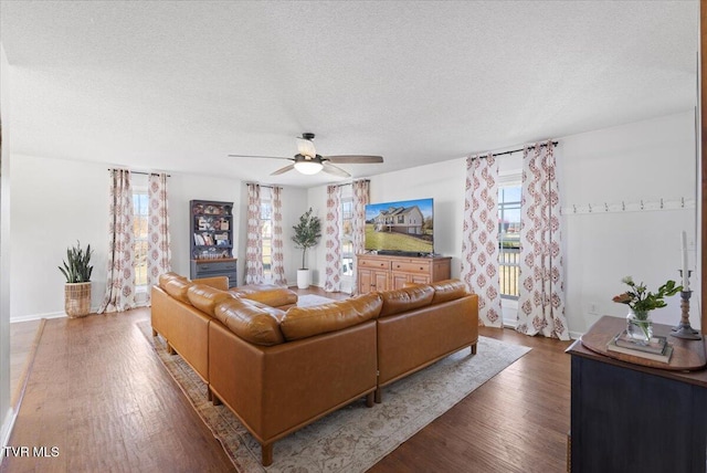 living area with ceiling fan, a textured ceiling, baseboards, and wood finished floors