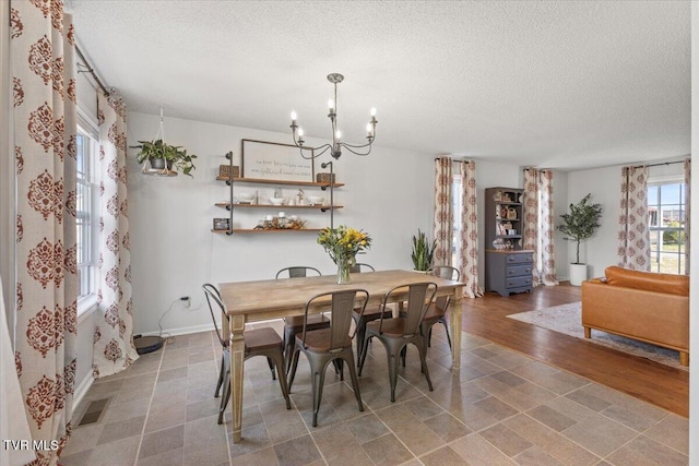 dining area with an inviting chandelier, visible vents, baseboards, and a textured ceiling