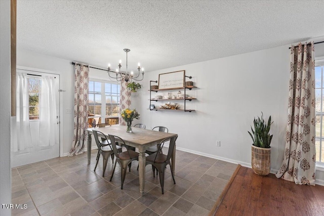 dining space with a chandelier, a textured ceiling, and baseboards