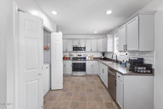 kitchen with dark countertops, appliances with stainless steel finishes, backsplash, and a sink