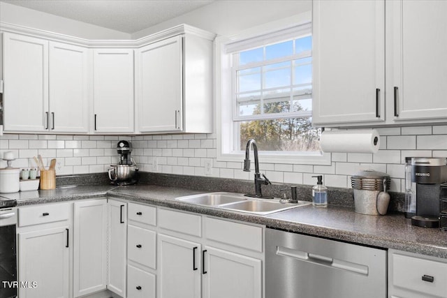 kitchen featuring dishwasher, tasteful backsplash, dark countertops, and a sink