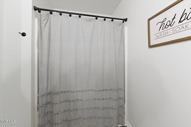 bathroom with a textured ceiling and a shower with shower curtain