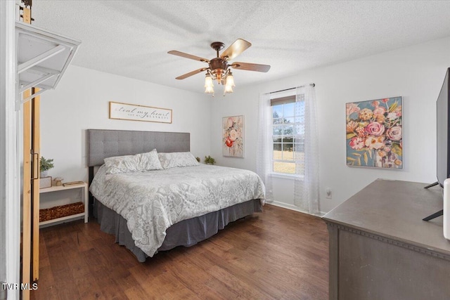 bedroom featuring dark wood-style floors, ceiling fan, a textured ceiling, and attic access