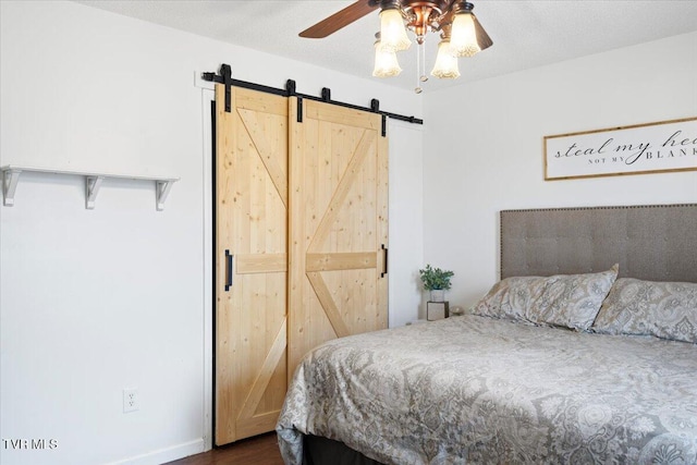 bedroom with a textured ceiling, a barn door, and a ceiling fan