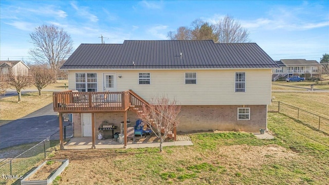 rear view of house with metal roof, a patio, a wooden deck, and fence