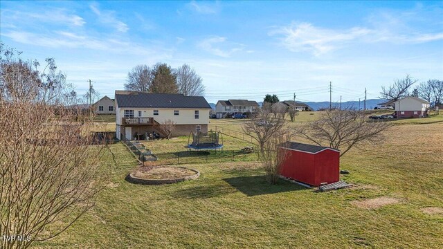 view of yard featuring a deck, a storage shed, an outdoor structure, stairs, and a trampoline