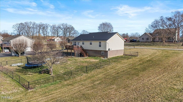 rear view of house featuring stairway, a trampoline, fence, a deck, and a yard