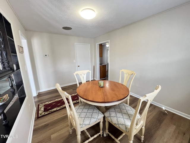 dining space with a textured ceiling, wood finished floors, and baseboards