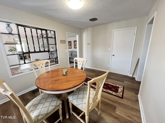 dining room with a textured ceiling, wood finished floors, visible vents, and baseboards