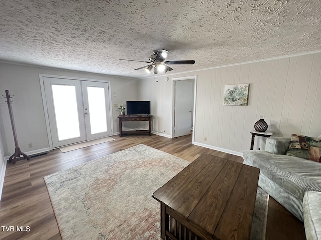 living area with a textured ceiling, wood finished floors, and french doors