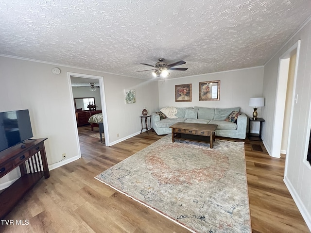 living room with ceiling fan, a textured ceiling, wood finished floors, and crown molding