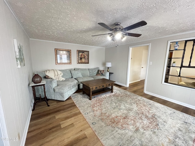 living room with ornamental molding, ceiling fan, a textured ceiling, and wood finished floors