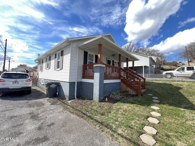 view of property exterior with covered porch, a yard, and stairway