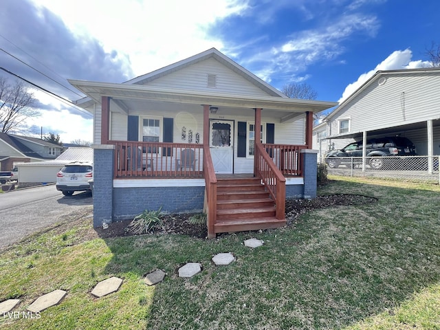 bungalow with covered porch, fence, and a front lawn