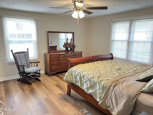 bedroom featuring light wood-style floors, multiple windows, and a textured ceiling