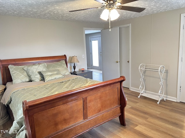 bedroom with light wood-type flooring, ceiling fan, and a textured ceiling