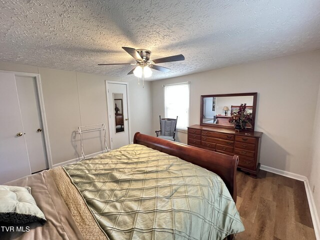 bedroom with a ceiling fan, a textured ceiling, baseboards, and wood finished floors