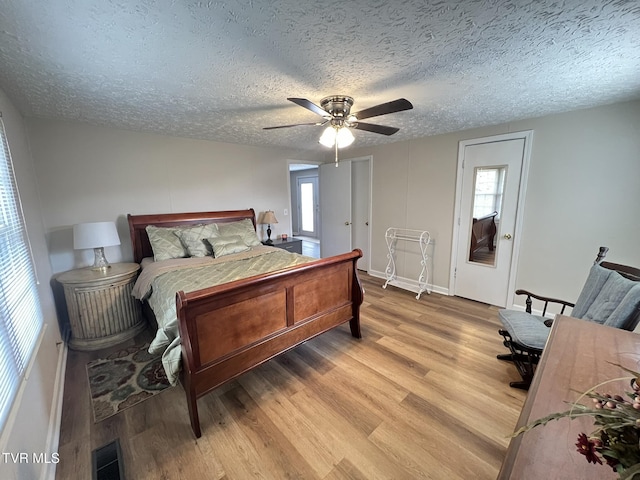 bedroom with a textured ceiling, light wood finished floors, and visible vents