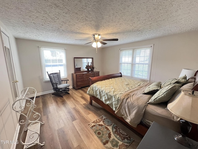 bedroom featuring ceiling fan, a textured ceiling, baseboards, and wood finished floors