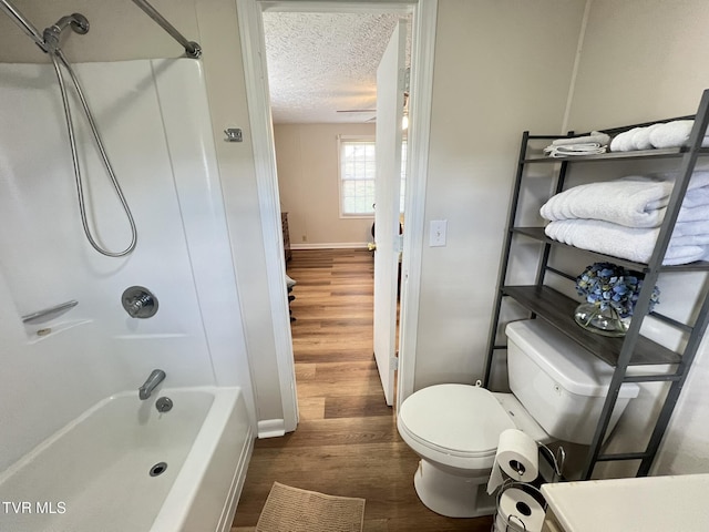 bathroom featuring toilet, a textured ceiling, shower / tub combination, wood finished floors, and baseboards