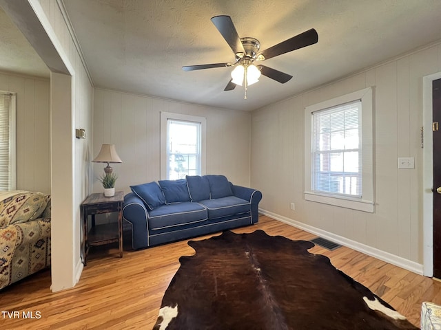 living room with light wood finished floors, plenty of natural light, visible vents, and a ceiling fan